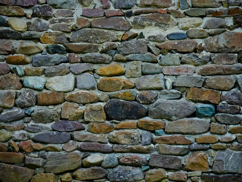 Mur en pierres de tailles et de teintes variées, assemblées au mortier